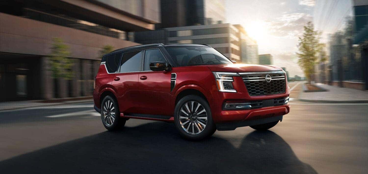 A red 2025 Nissan Armada quickly making a turn on the road.