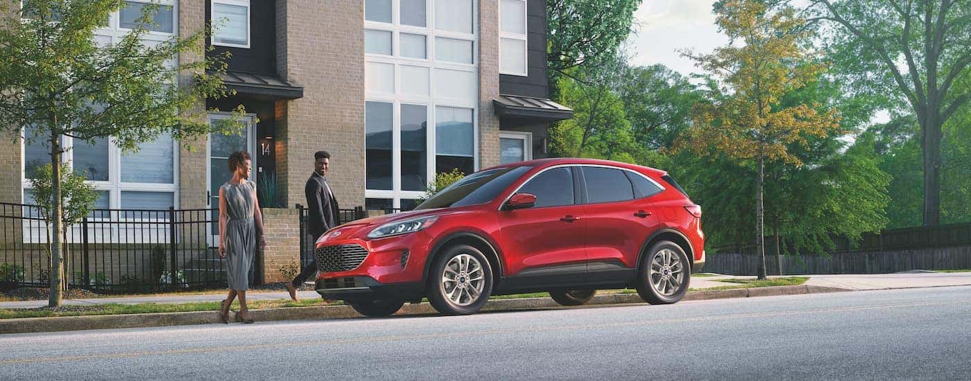 A red 2022 Ford Escape is shown from the side next to two people.
