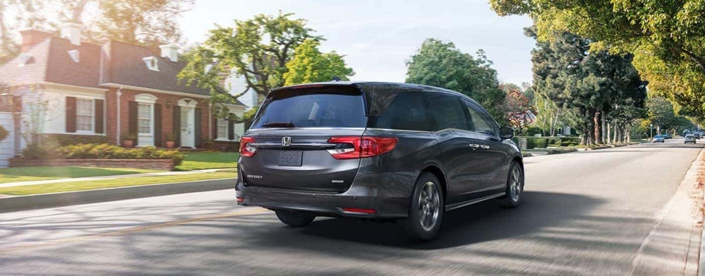 A Grey 2022 Certified Pre-Owned Honda Odyssey is shown driving on a suburban street.