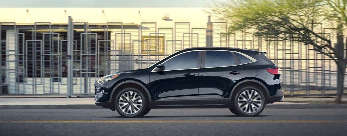 Side view of a black 2022 Ford Escape driving on a city street.