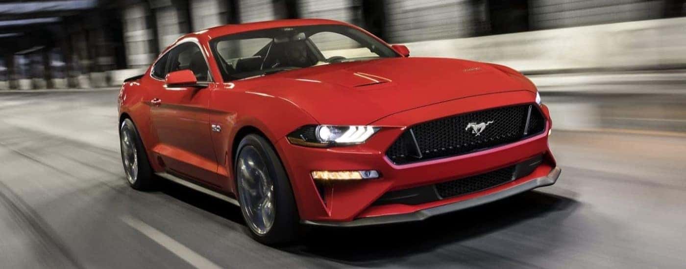 Head-on view of a red 2023 Ford Mustang GT driving to view used cars for sale.