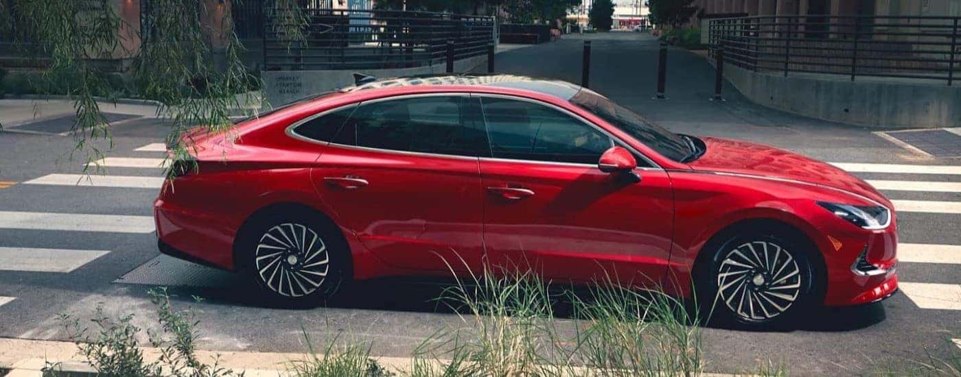 A red 2021 Hyundai Sonata Hybrid driving through the city to view used cars for sale near Farragut.