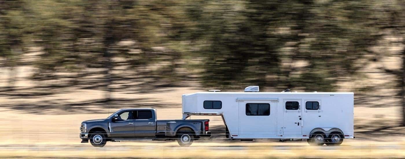 A gray 2023 Ford F-350 Lariat is shown towing a trailer.