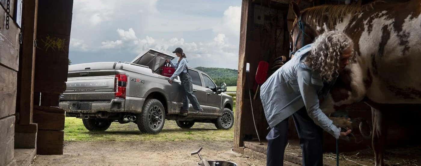 A Silver 2024 Ford F-250 Platinum is shown parked outside of a barn.