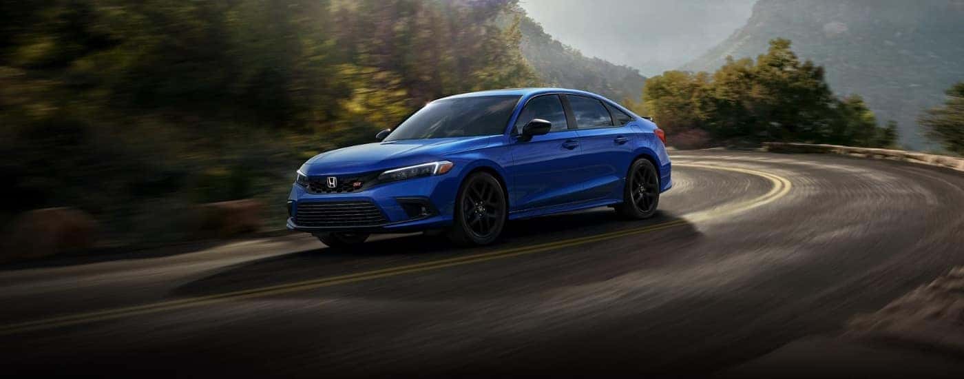 A Blue 2023 Honda Civic Si is shown rounding a corner.