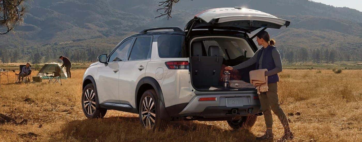 White 2023 Nissan Pathfinder is shown near a camp site.
