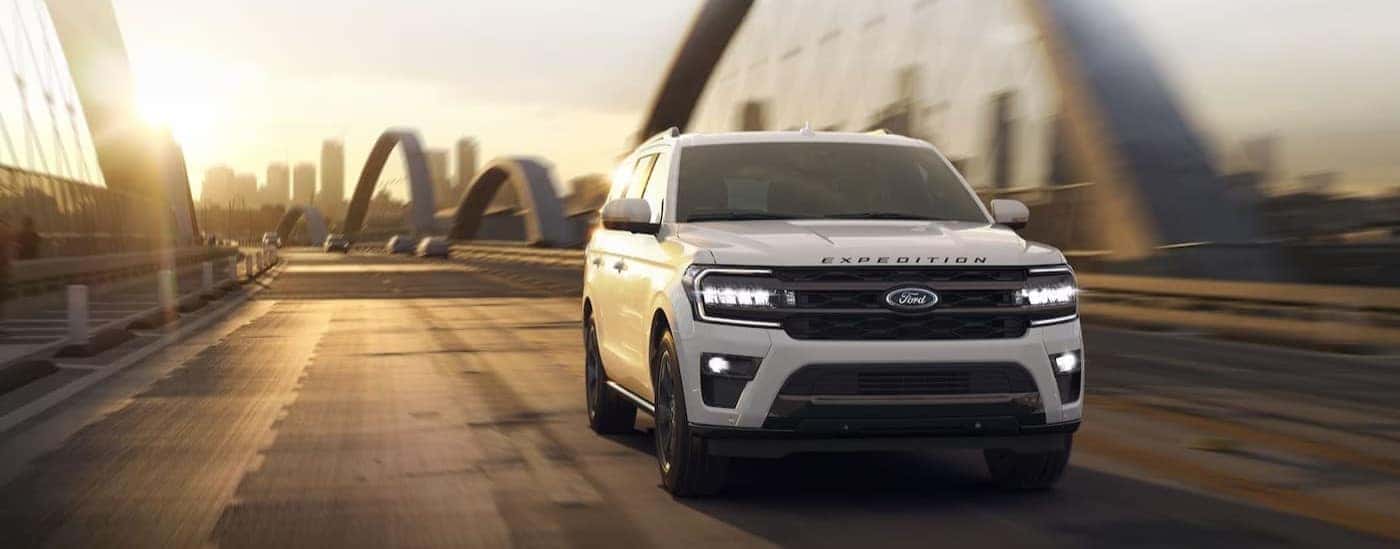 A white 2023 Ford Expedition is shown driving on a bridge.