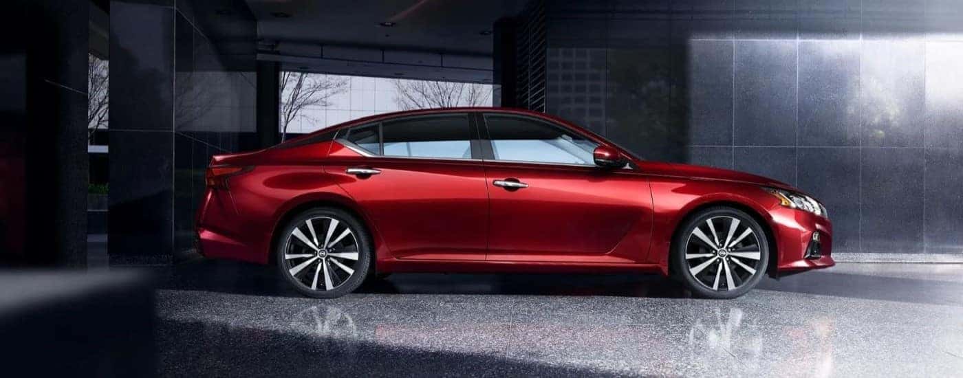 Side right angled view of a red 2019 Nissan Altima parked inside a building.