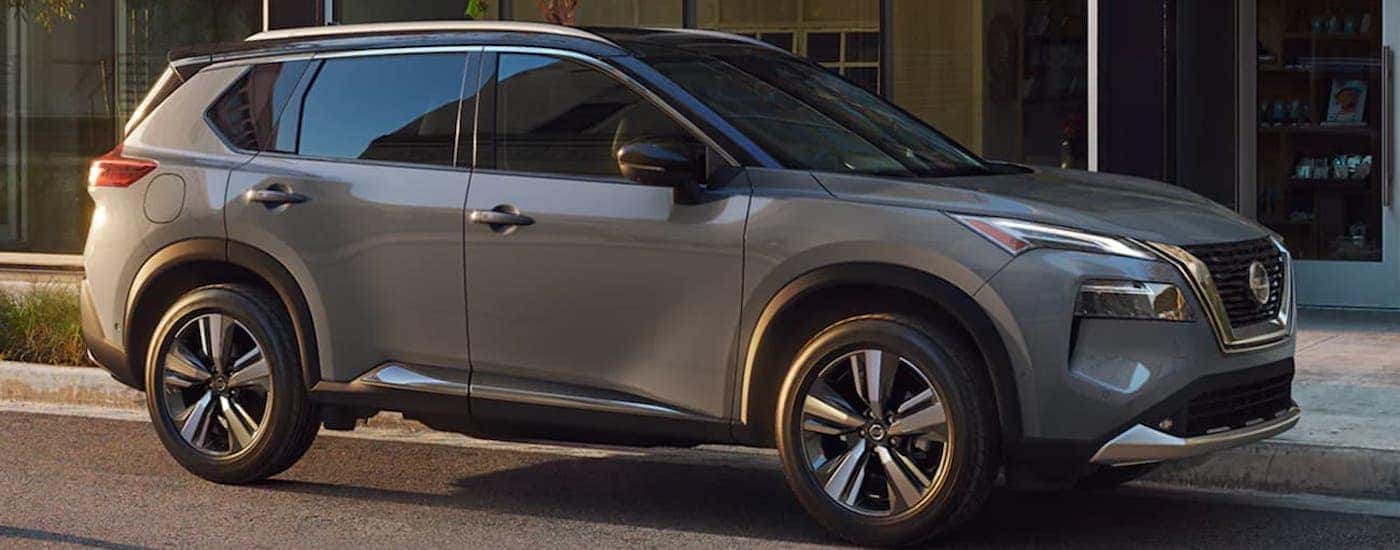 Side right angled view of a grey 2021 Nissan Rogue parked outside a building.
