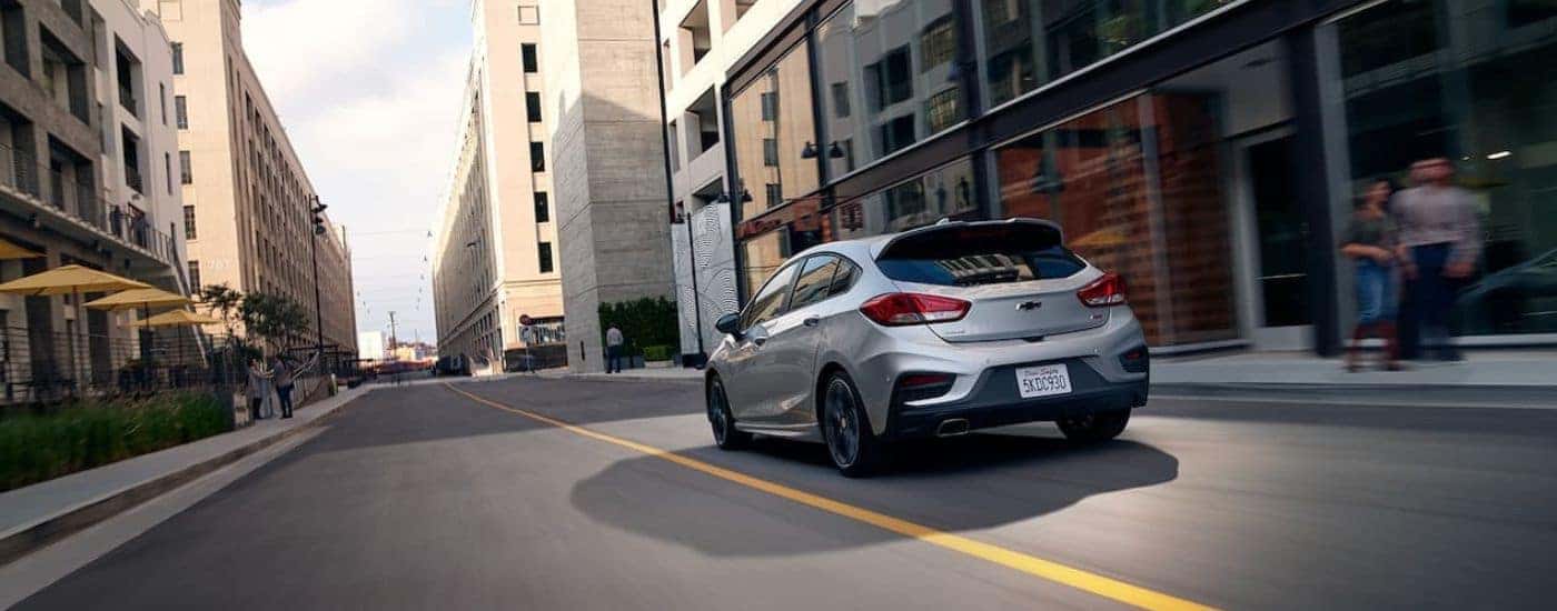 A silver 2019 Chevy Cruze RS is shown driving on a city street.