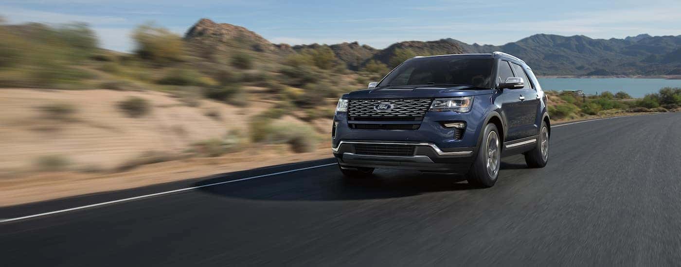 Black 2018 Ford Explorer driving down a road near a lake