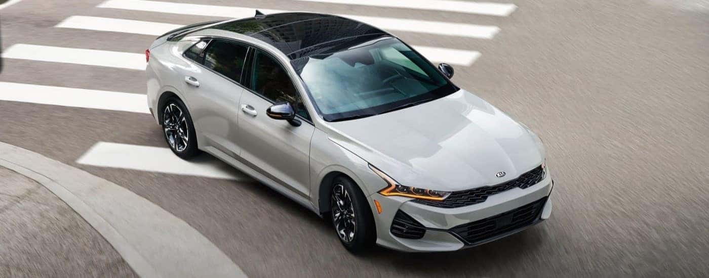 White 2022 Kia K5 driving through an intersection.