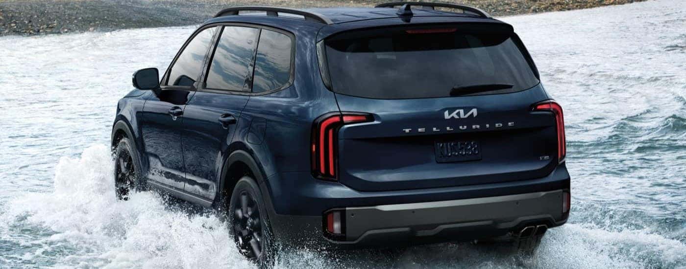 Blue 2023 Kia Telluride driving through a shallow river.