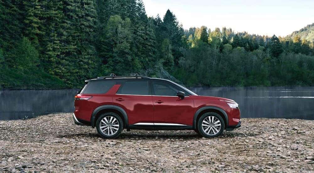 A red 2023 Nissan Pathfinder is shown parked near a lake.
