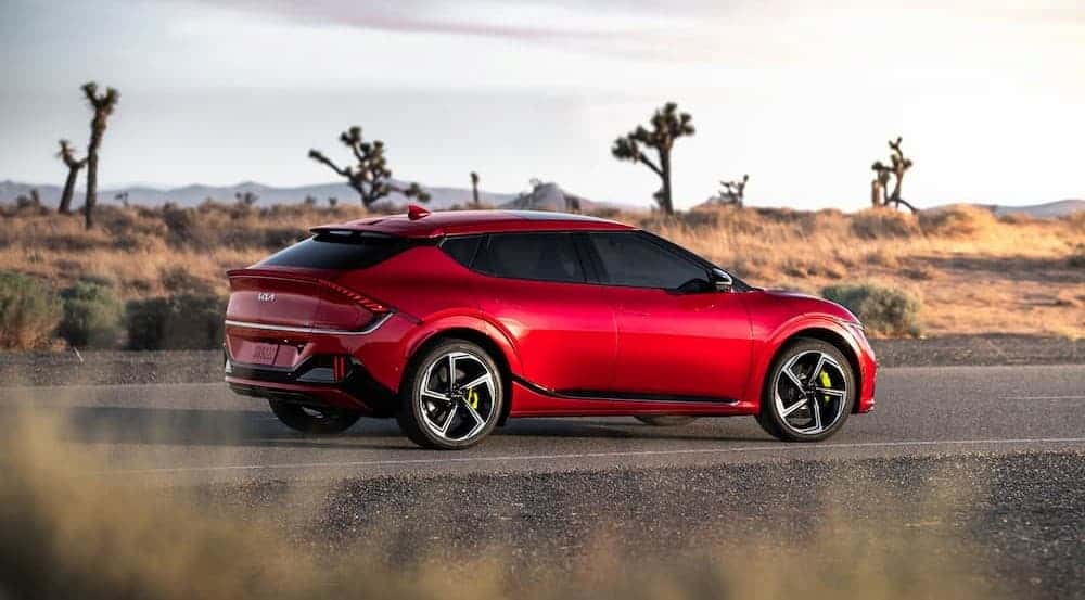A red 2023 Kia EV6 is shown parked on a backroad.