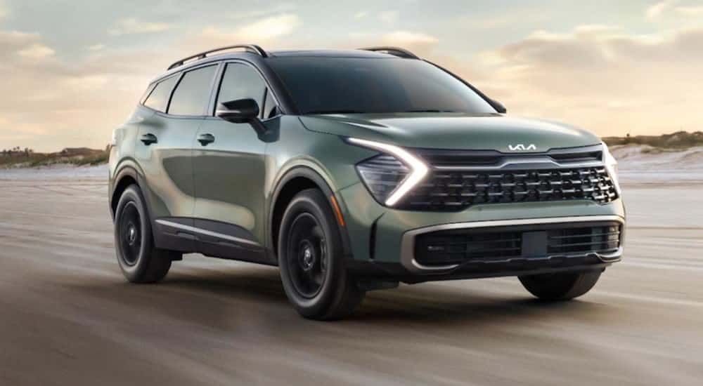 A green 2024 Kia Sportage is shown driving off-road.