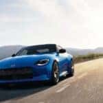 A blue 2024 Nissan Z is shown driving to view certified pre-owned cars for sale.