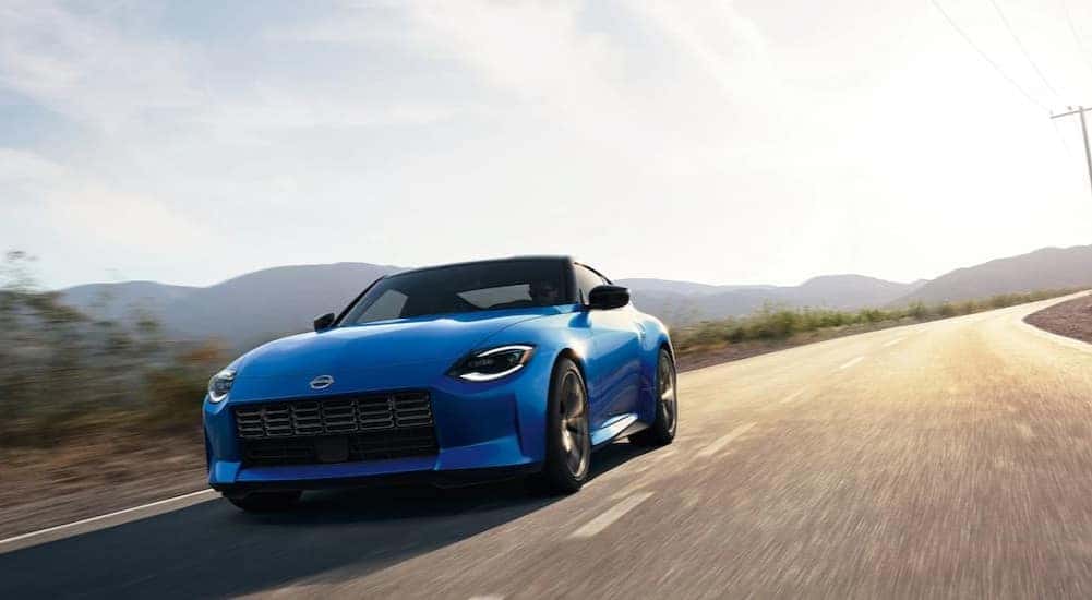 A blue 2024 Nissan Z is shown driving to view certified pre-owned cars for sale.