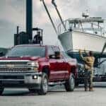 The trailer of a maroon 2018 Chevy Silverado 2500 HD is being loaded with a boat.