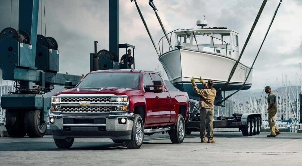The trailer of a maroon 2018 Chevy Silverado 2500 HD is being loaded with a boat.