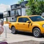 A yellow 2022 Ford Maverick parked by a curb.