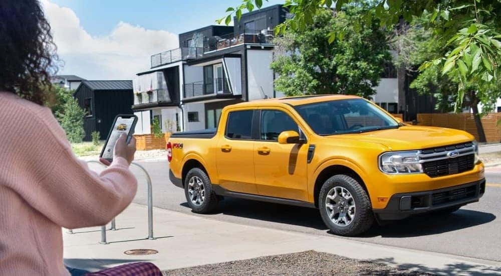 A yellow 2022 Ford Maverick parked by a curb.