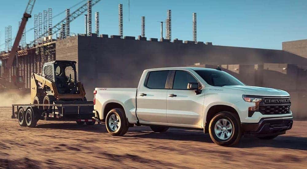A white 2023 Chevy Silverado 1500 towing a trailer.