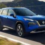 A blue 2021 Nissan Rogue driving down a highway
