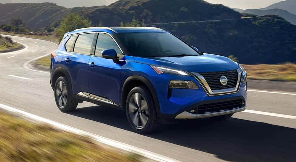 A blue 2021 Nissan Rogue driving down a highway