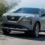 A gray used 2021 Nissan Rogue driving down a street