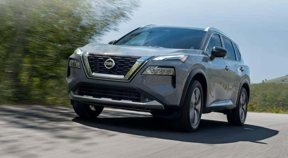 A gray used 2021 Nissan Rogue driving down a street