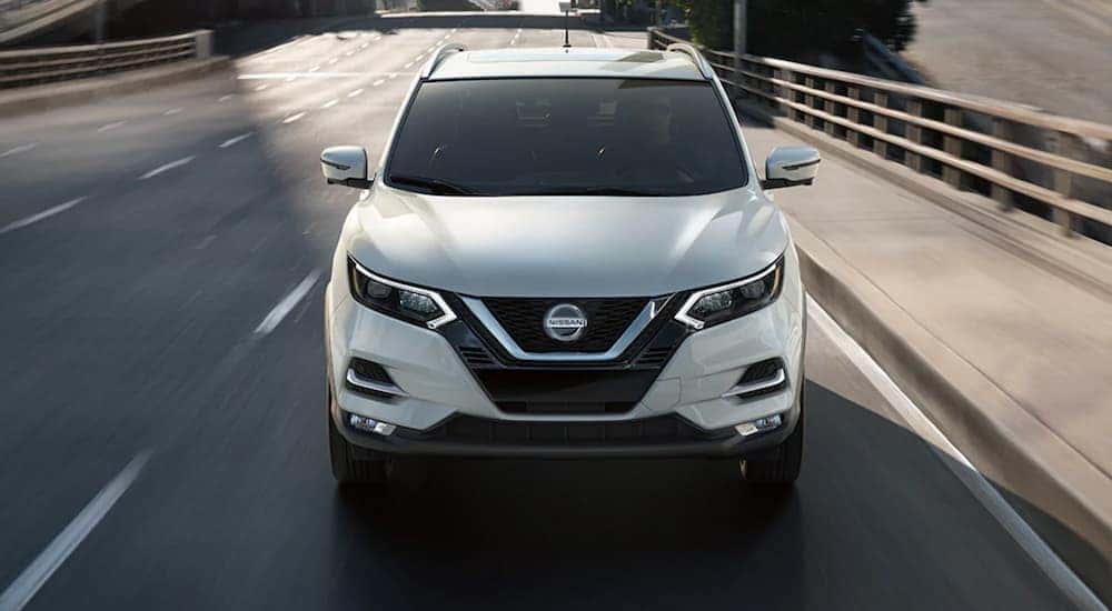 A white used 2021 Nissan Rogue driving down the street