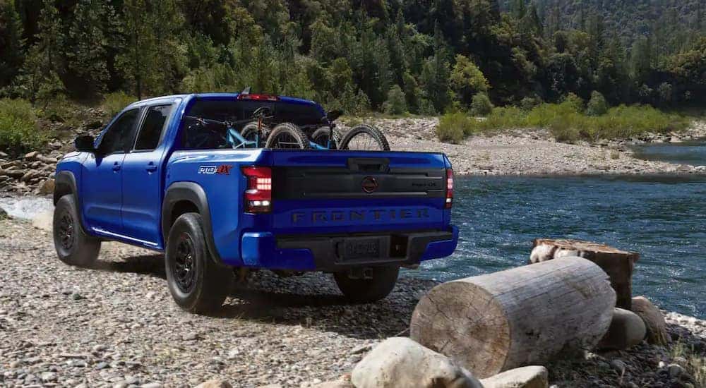 A blue 2025 Nissan Frontier parked off-road near a lake