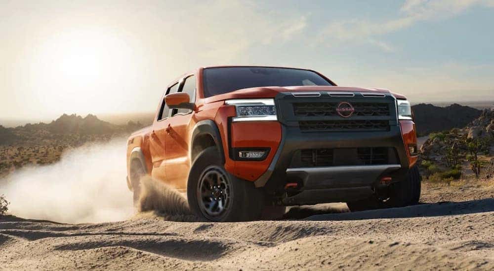 An orange 2025 Nissan Frontier off-roading on sand