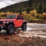 a red used 2024 Jeep Wrangler Rubicon parked near a stream