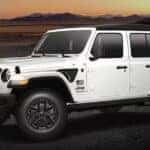 A white 2023 Jeep Wrangler Freedom Edition parked off-road.