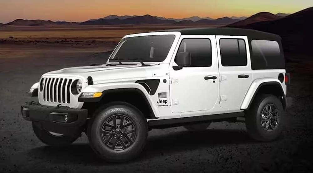 A white 2023 Jeep Wrangler Freedom Edition parked off-road.