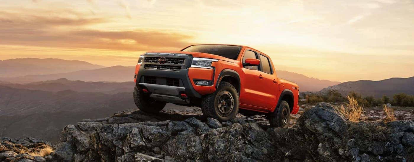 An orange 2025 Nissan Frontier off-roading on rocky terrain