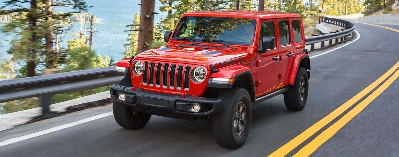 A red used 2021 Jeep Wrangler Rubicon Unlimited driving down a road