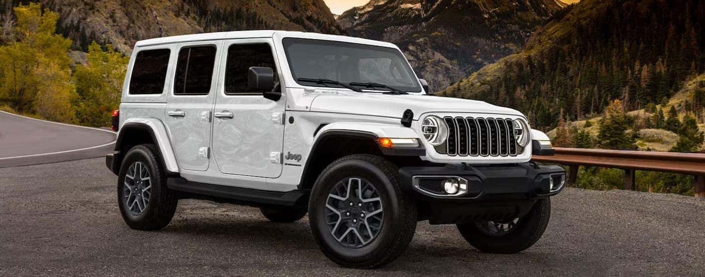 A white 2025 Jeep Wrangler parked on gravel