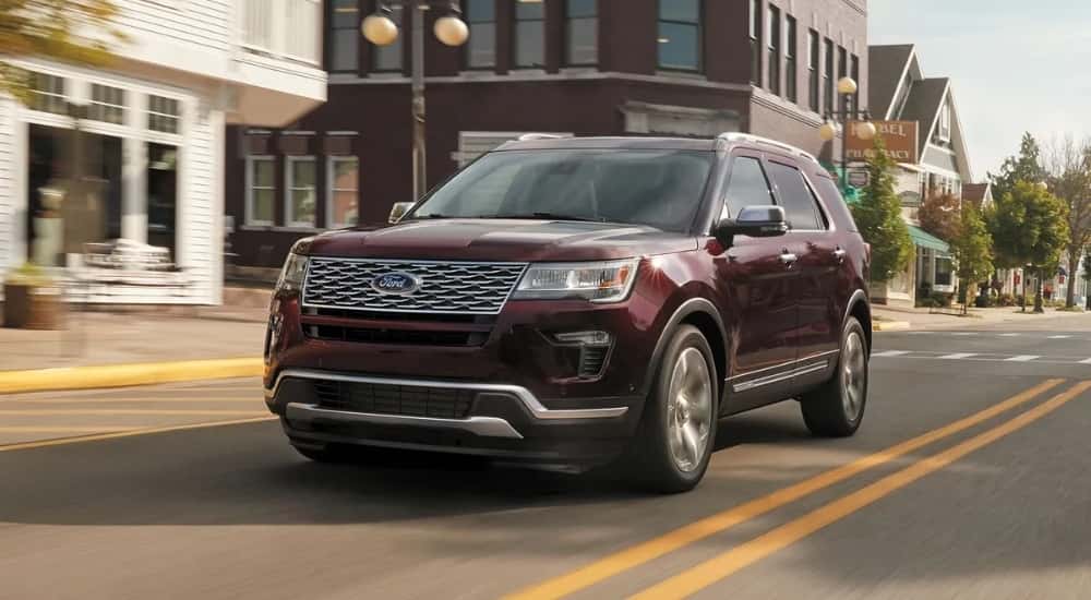 A burgundy 2019 Ford Explorer driving past a pharmacy.