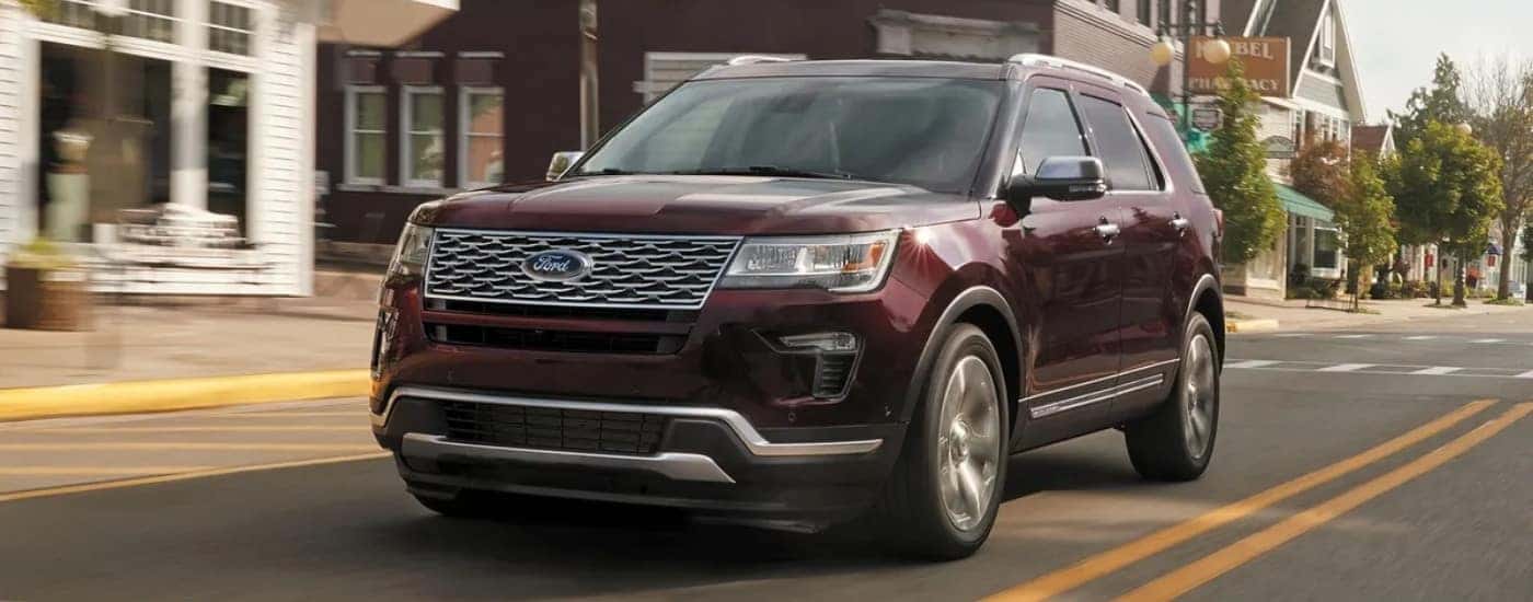 A burgundy 2019 used Ford Explorer for sale driving past buildings.