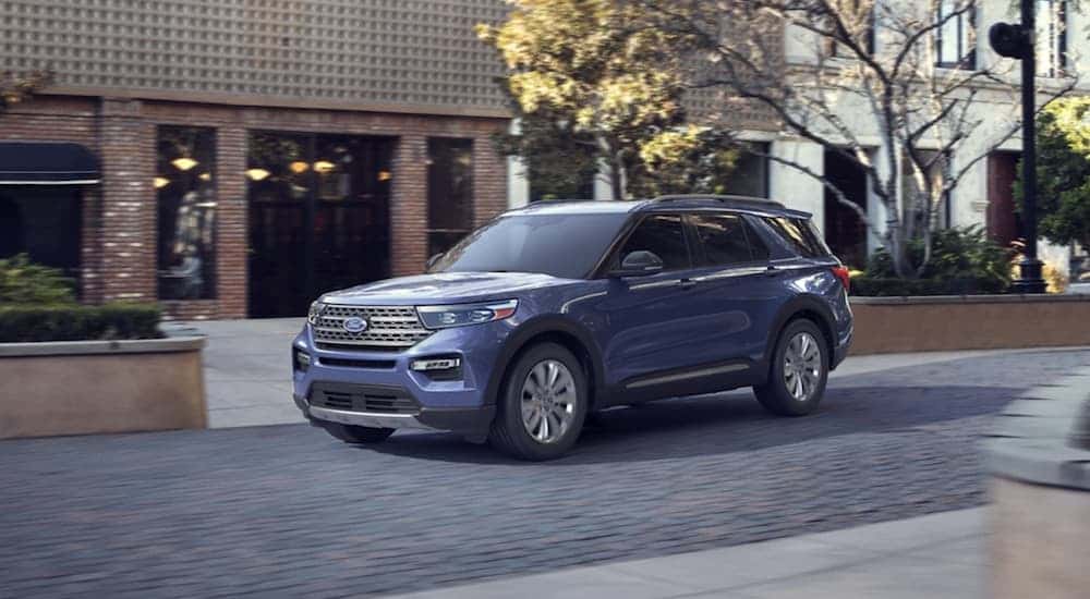 A used blue 2020 Ford Explorer for sale driving in a city.