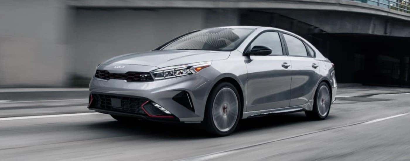 A silver 2024 Kia Forte GT driving down a city street