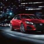 A red used 2023 Nissan Altima SR driving in a city at night