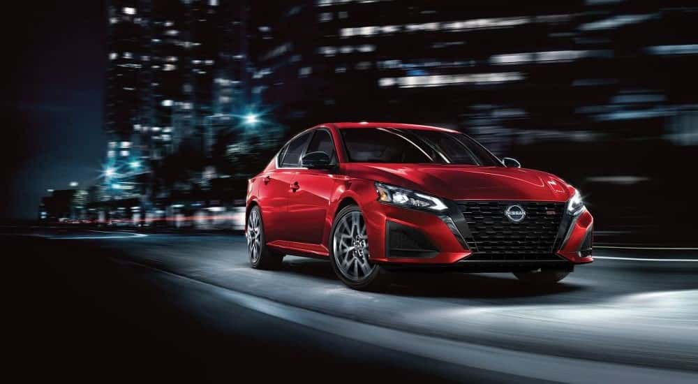 A red used 2023 Nissan Altima SR driving in a city at night