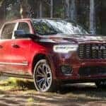 A red used 2025 Ram 1500 parked off-road on a wooded trail