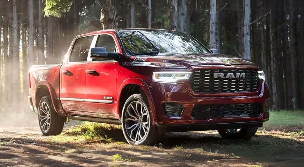 A red used 2025 Ram 1500 parked off-road on a wooded trail