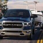 A blue 2024 Ram 1500 towing a boat.