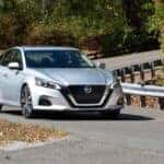 A silver used 2021 Nissan Altima driving on a curved road